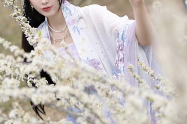 花海深处仙子立，紫纱轻舞映白樱。她指尖轻触春枝，是人间四月天里，最温柔的一抹惊鸿。