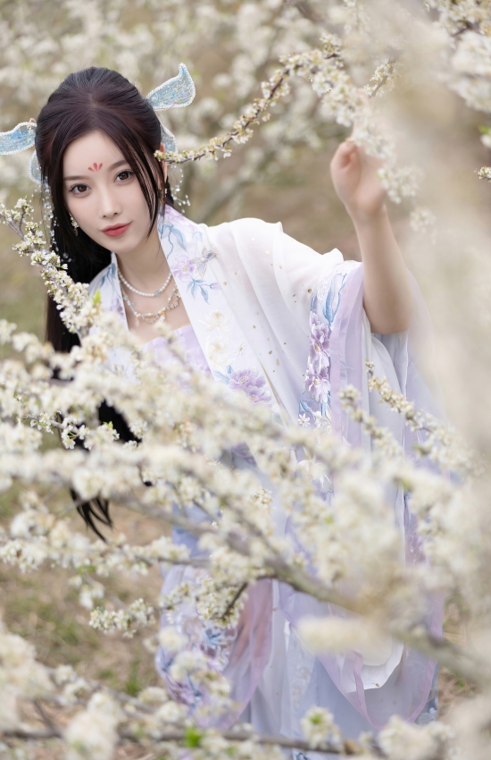 花海深处仙子立，紫纱轻舞映白樱。她指尖轻触春枝，是人间四月天里，最温柔的一抹惊鸿。
